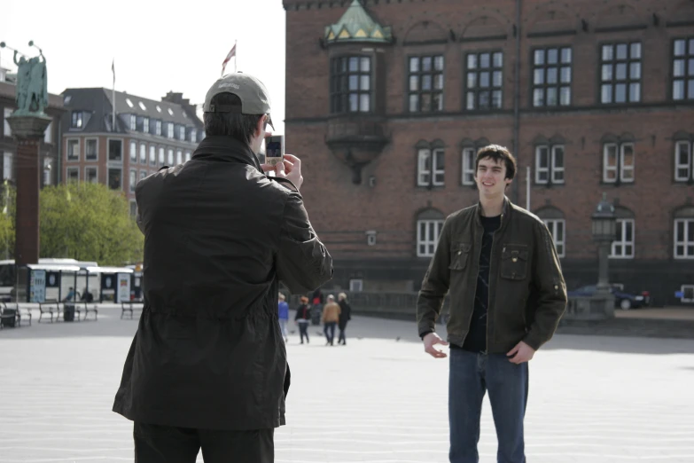 a person is taking pictures while another man is wearing a jacket