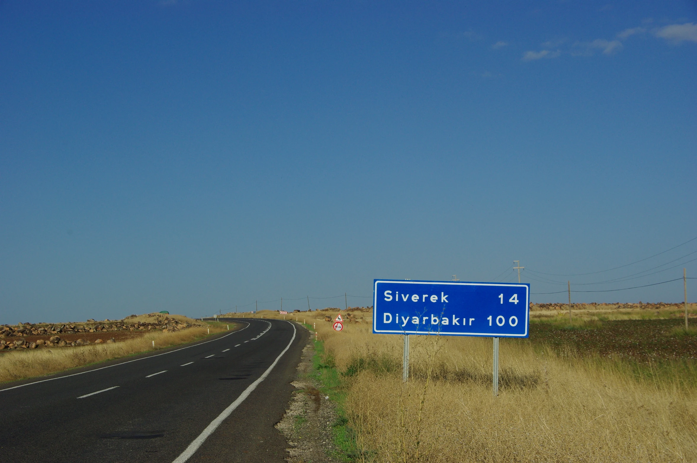 blue sign on the side of an empty highway