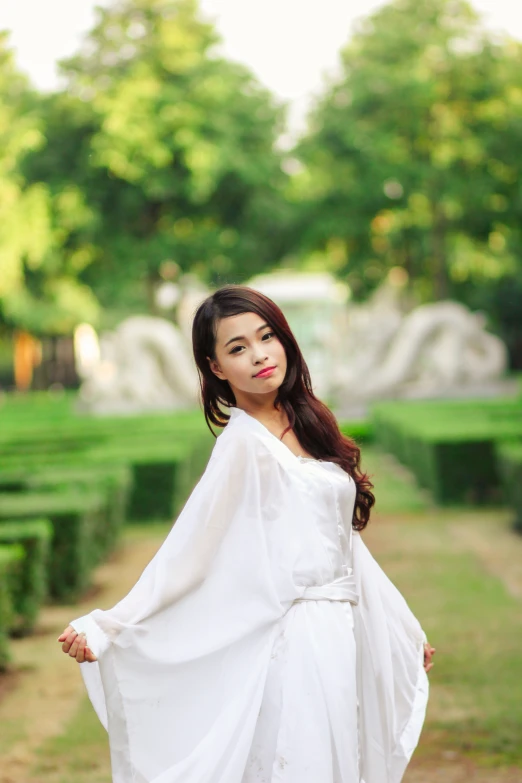 a woman standing in front of a hedged walkway