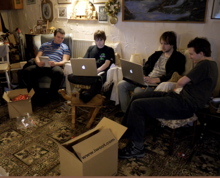 four people are sitting on a couch with their laptops