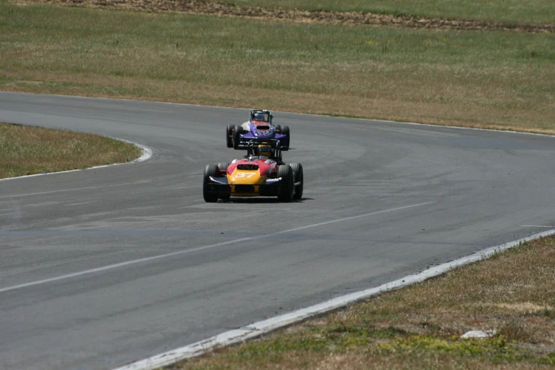 a race car speeding down a curvy road in a grassy field