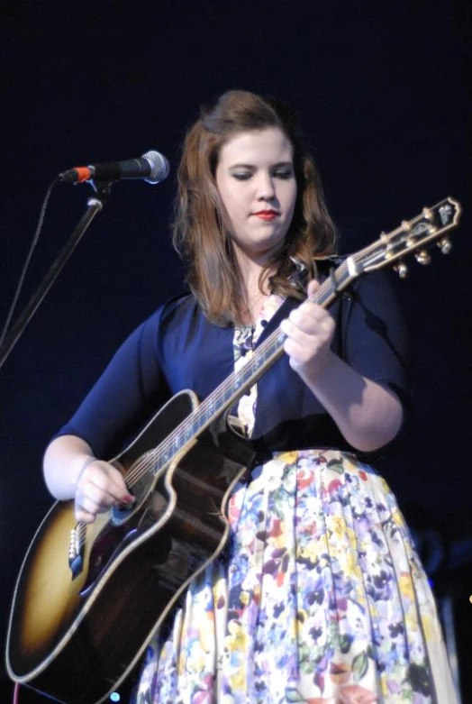 a woman playing an acoustic guitar on stage