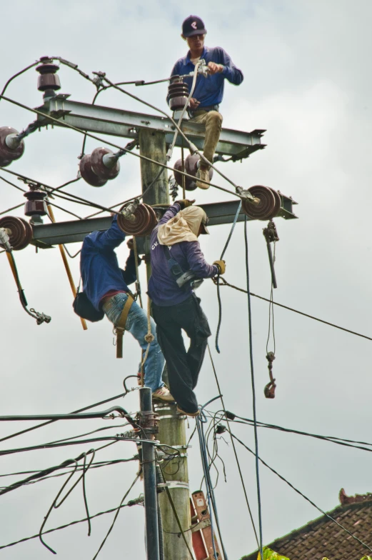 some people standing on top of a power pole