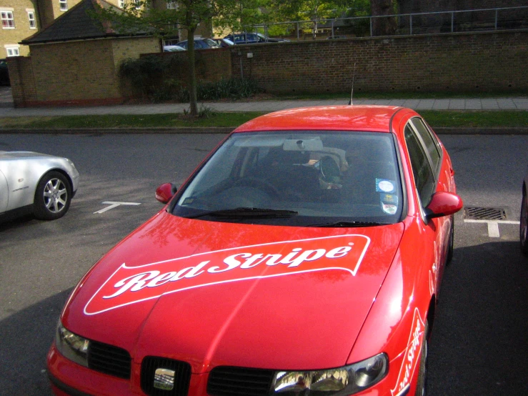 a red car with a ride ship on it sitting in the street