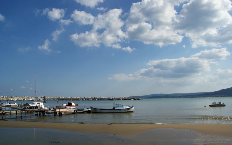 boats in a bay under cloudy skies near a beach