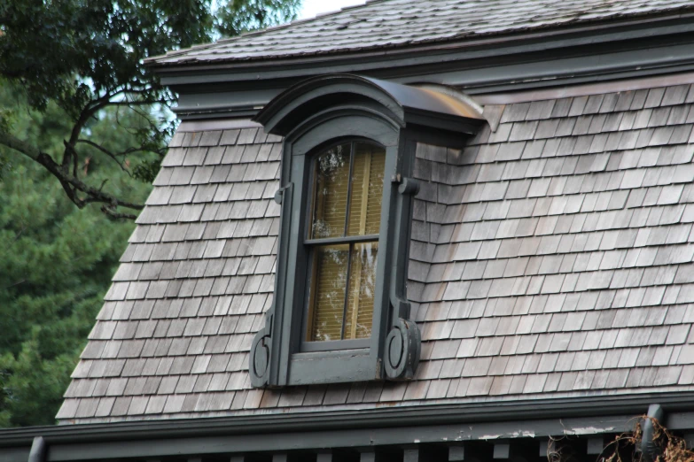 an older style house with black dormer windows and wood shingles