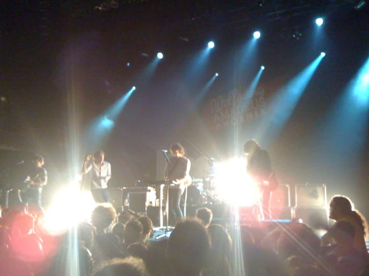 two guys on a stage with instruments singing in front of a crowd