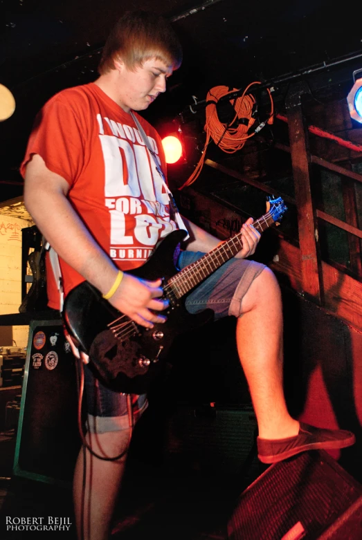 a man is sitting on a ledge playing his guitar