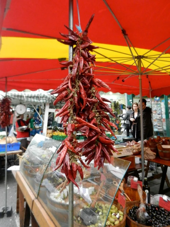 a view of some red chili peppers hanging from a pole at an outdoor market