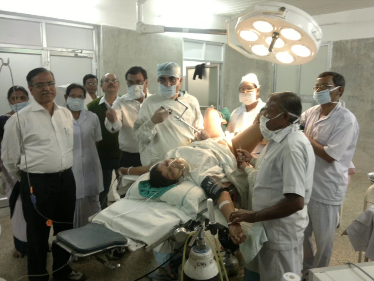 a group of doctors in scrubs and masks standing around a patient