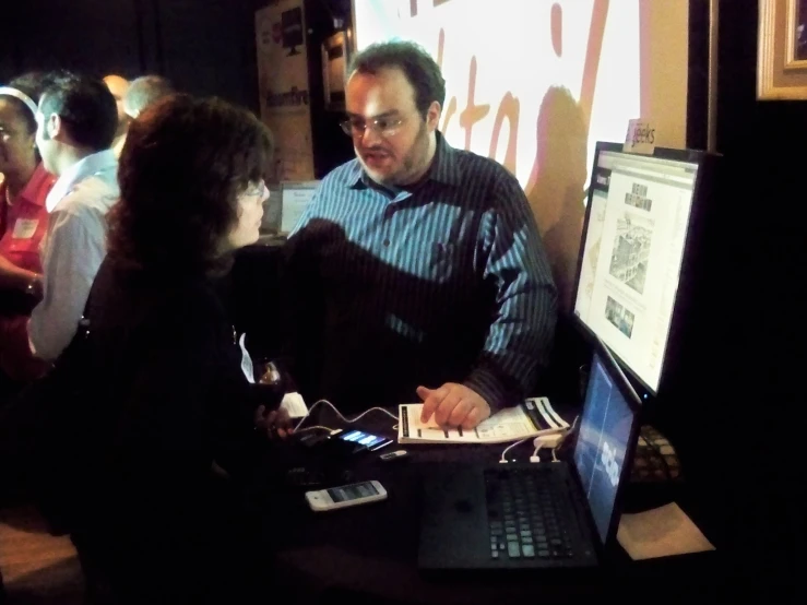 a man standing next to a woman in front of a laptop computer