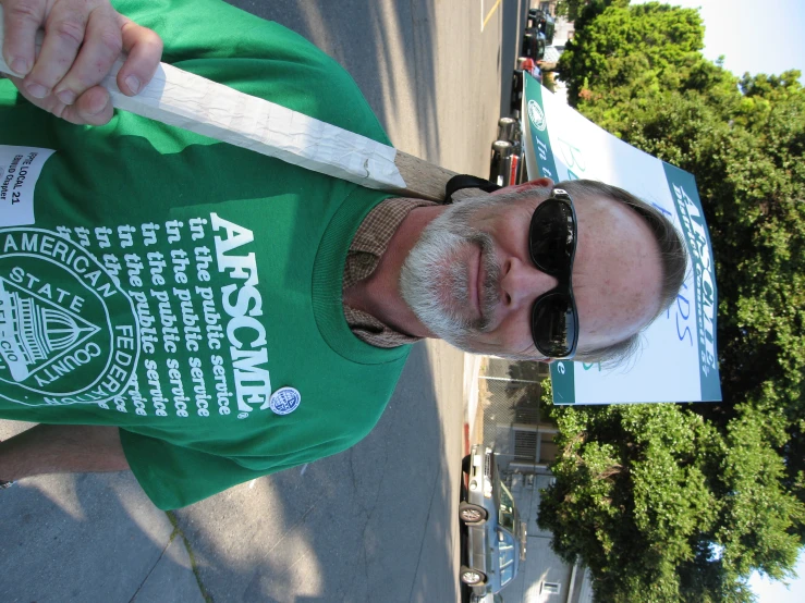 a man with a sign and sunglasses holding up a white paddle