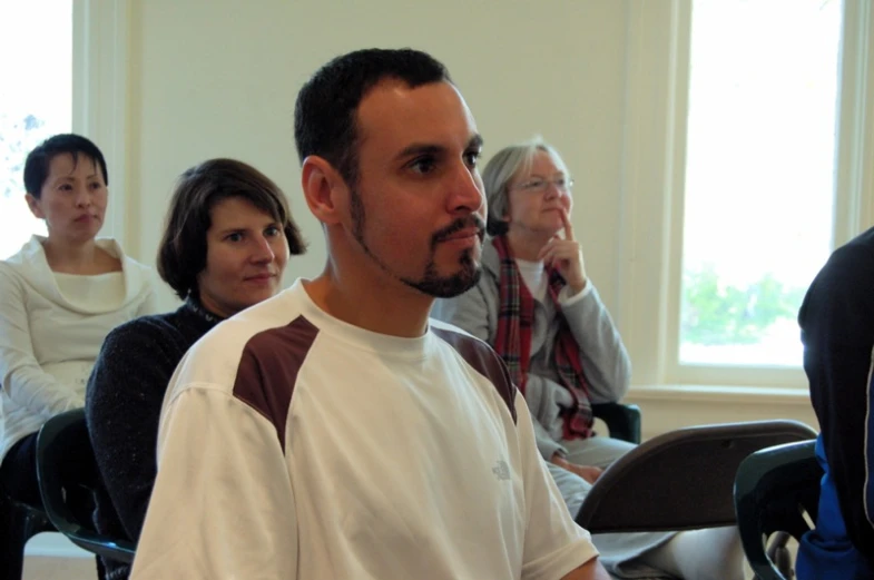 several people are sitting down in chairs with one man in front