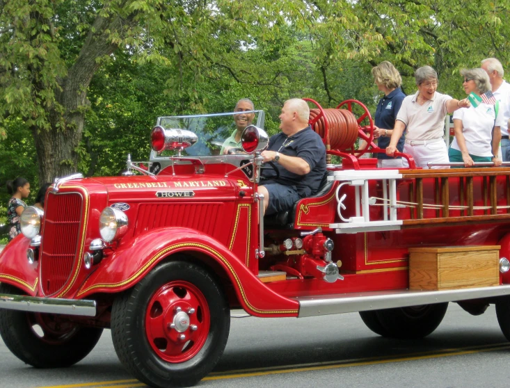 a vintage fire truck is on the street with people