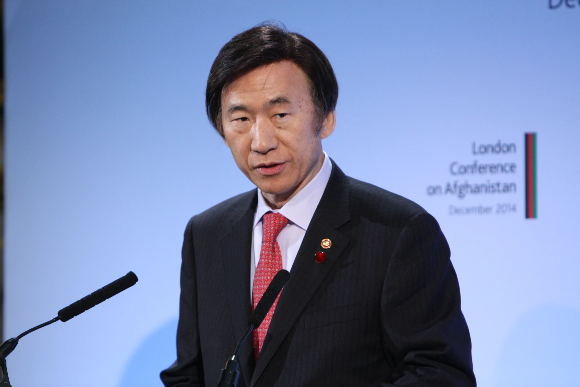 an asian man is speaking at a podium