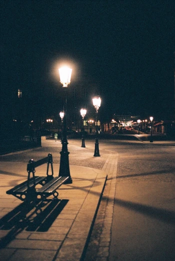 there is a bench that sits alone on the street at night
