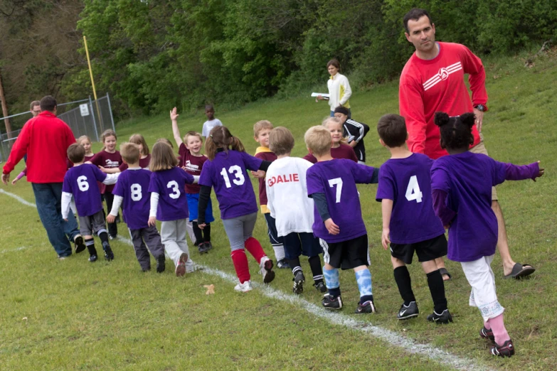 young children being coached by a coach on a field