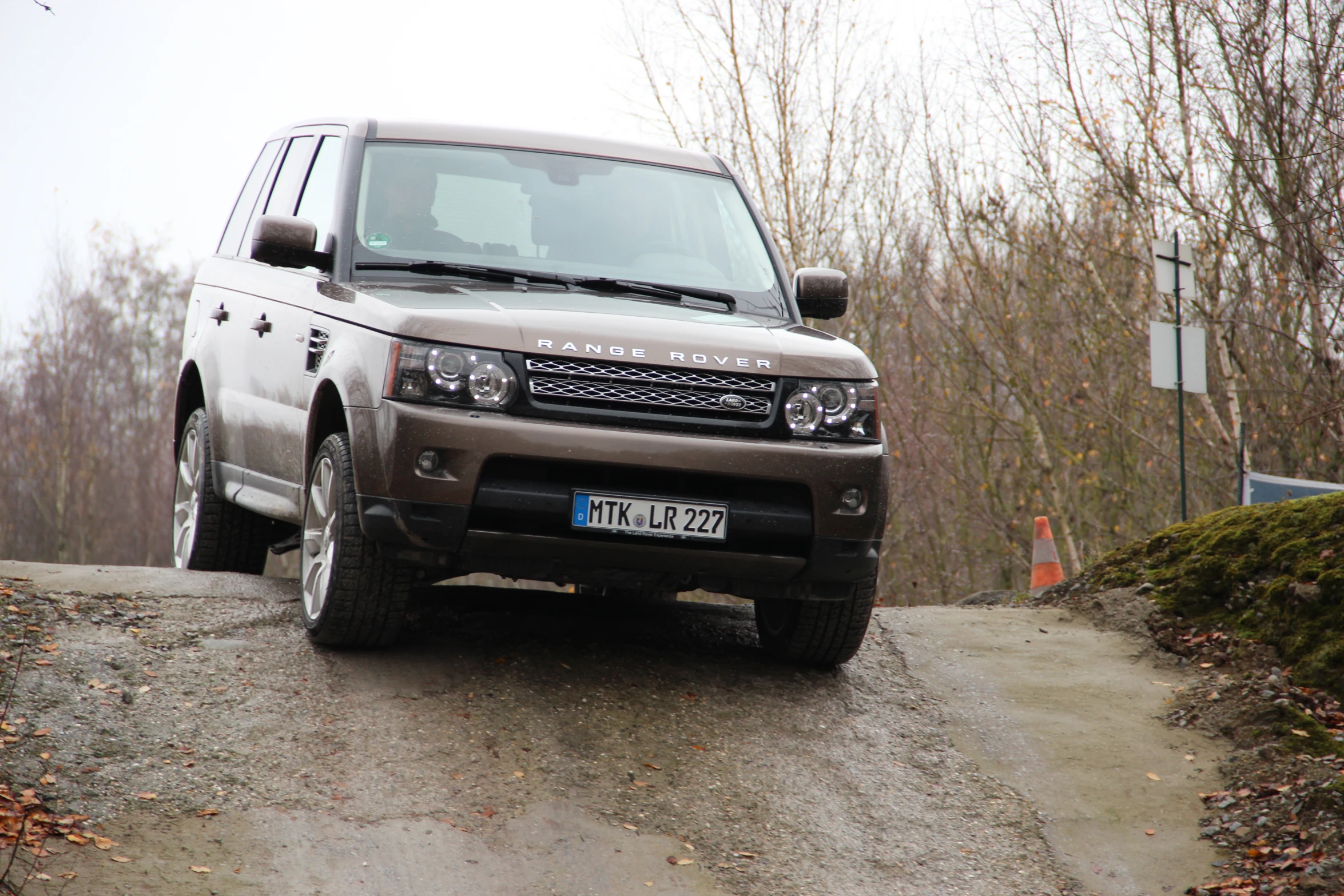 a grey range rover is parked on a narrow road