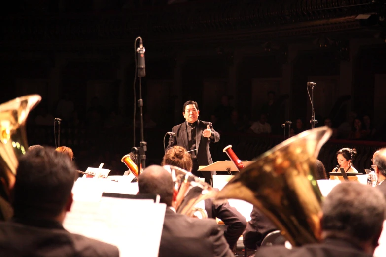 conductor in a dark concert setting with orchestra playing instruments