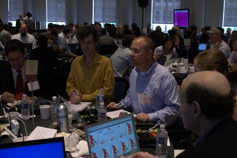 a group of people sitting at tables with laptops