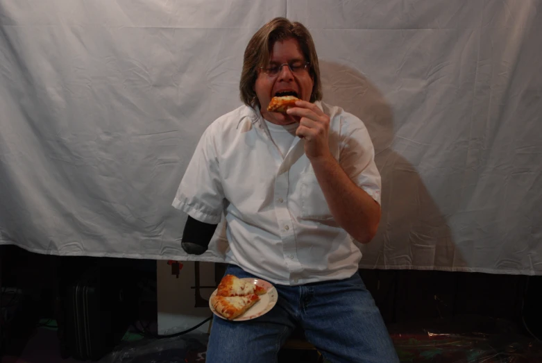 a person in a white shirt holds a plate and puts his mouth open