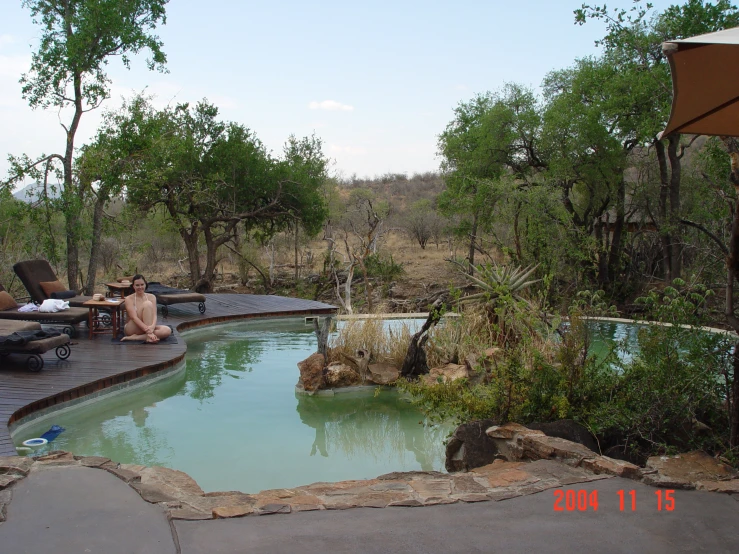 two people sitting near the edge of a swimming pool in an outdoor area