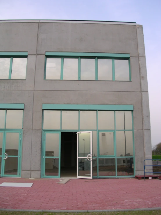 a large grey building with an open door next to a walkway