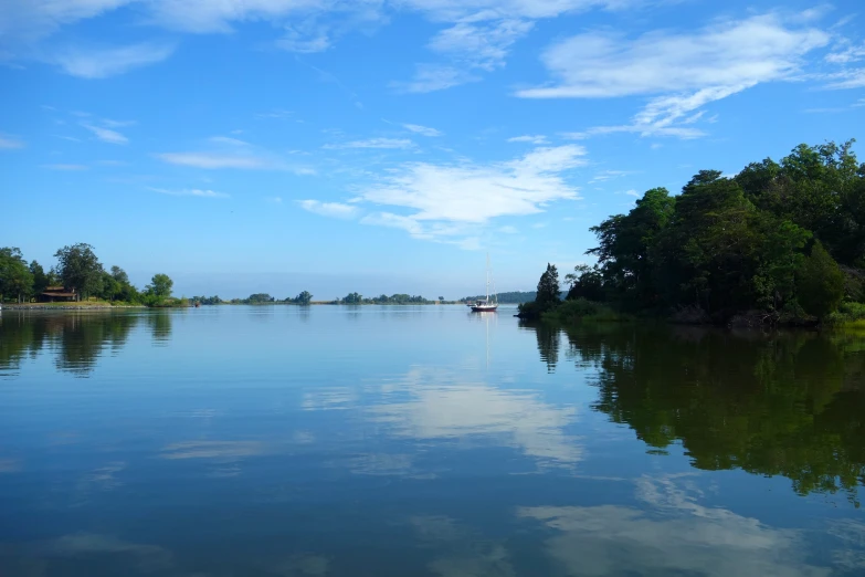 sailboats are moored in calm water with blue skies above