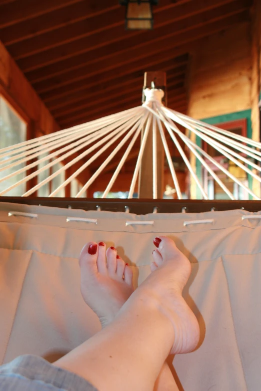 a person with red nail polish laying in a hammock