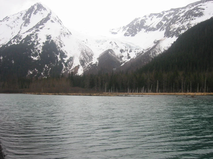 an almost empty lake with tall mountains in the background