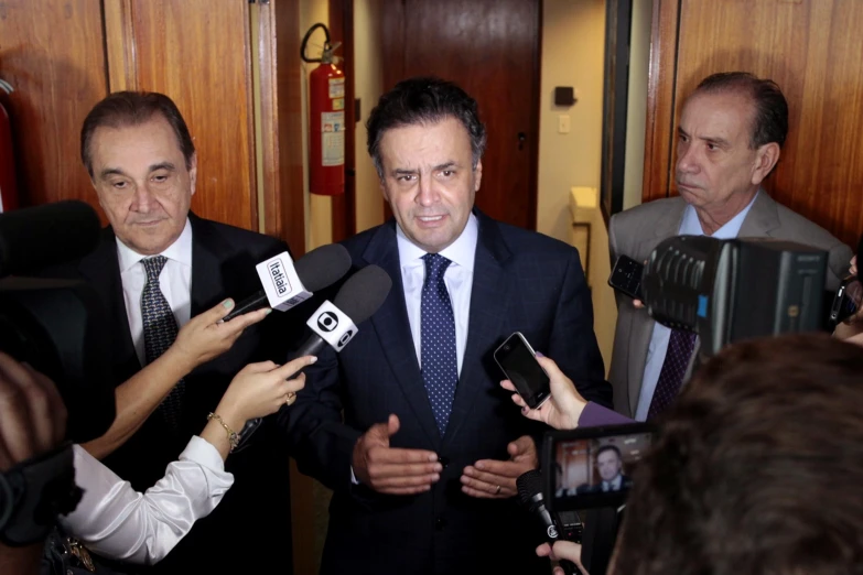 a man wearing a tie standing with two reporters