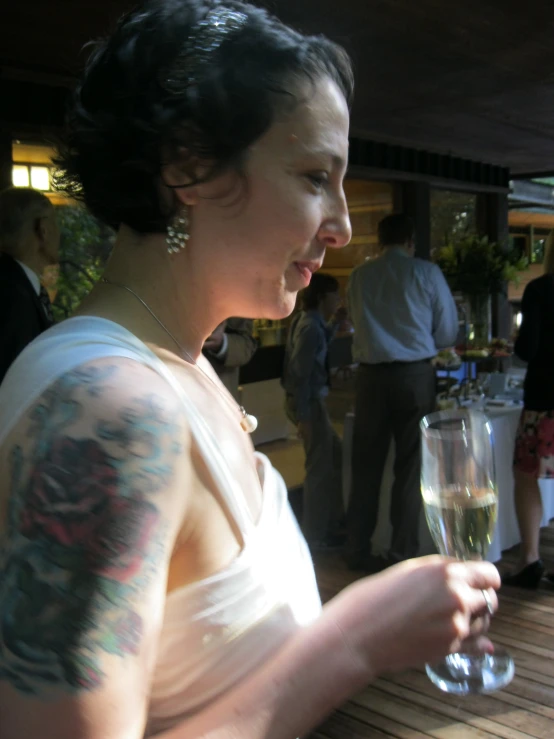 a woman with a tattooed arm drinking wine
