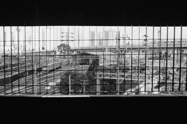 a black and white image of an industrial train station through some cage