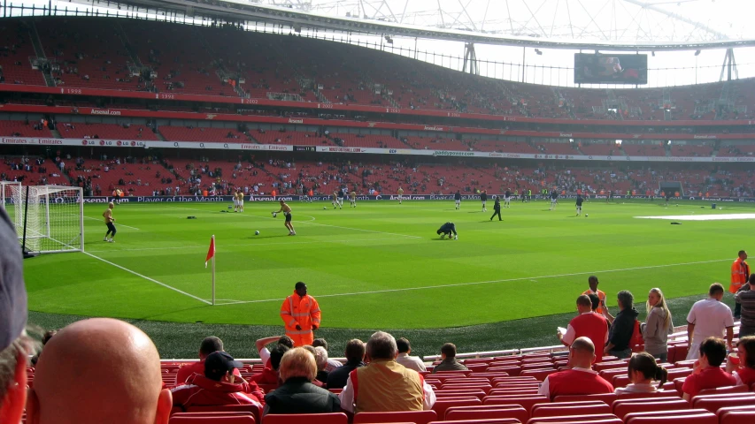 a crowd of people standing in a stadium near a soccer field