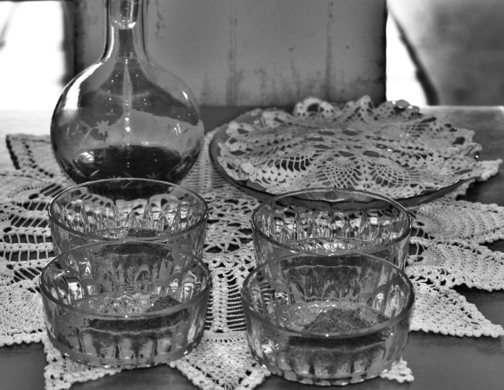 a glass pitcher next to a bowl on a lace doily