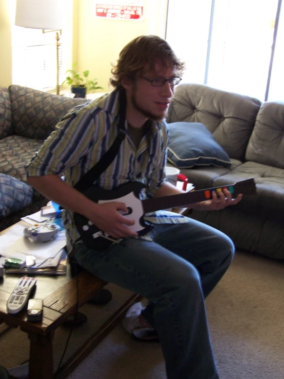 the man is playing the guitar at home