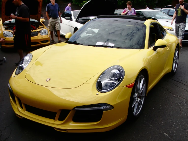 a yellow car sitting next to other cars at an event