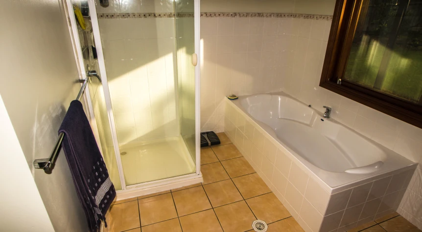 a very clean and white tiled bathroom with a small mirror