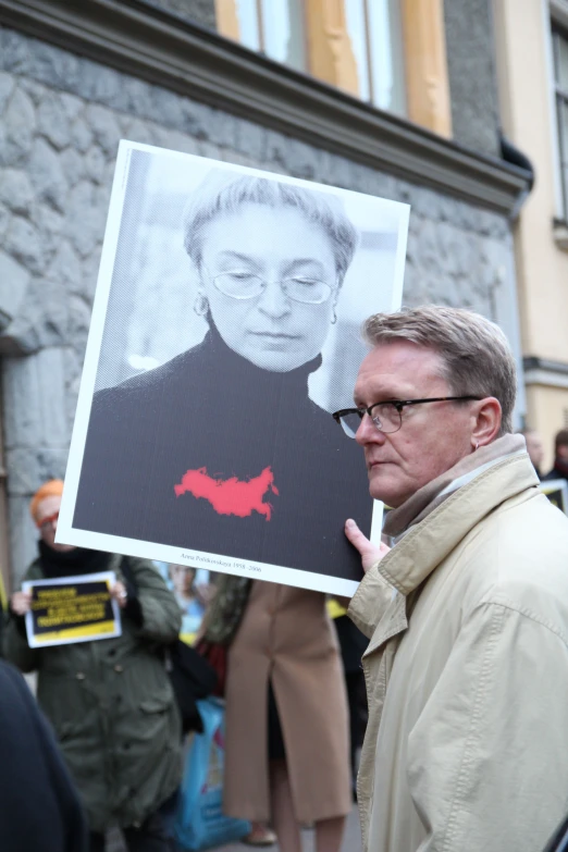 man holding up a picture of a person with a devil face on it