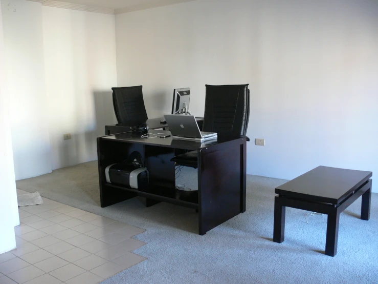 an office table and two chairs with computers on top