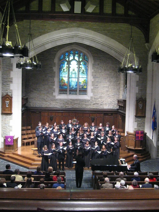 an old church with choirs and chairs, there are stained glass windows above the pew