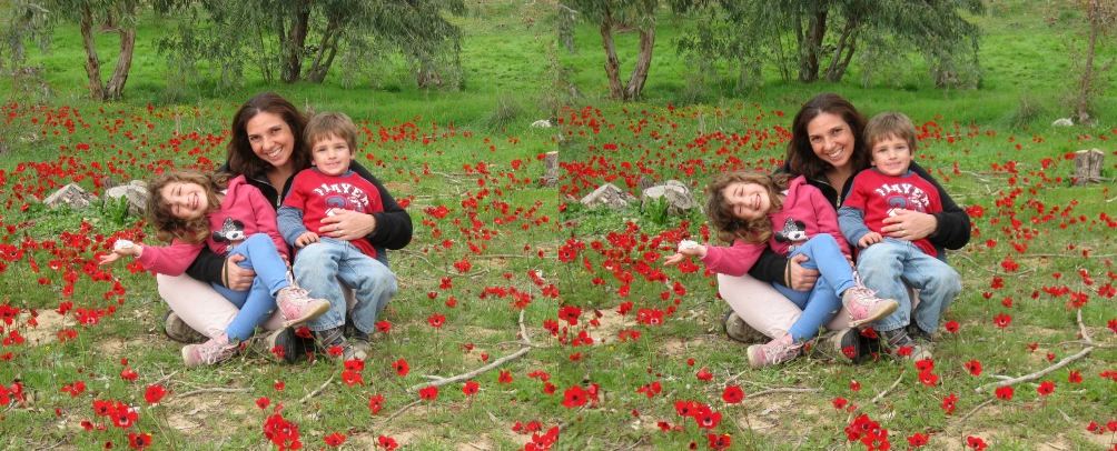 a family of five sits in a field full of red flowers