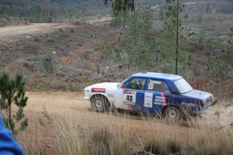 a car driving down a dirt road next to grass