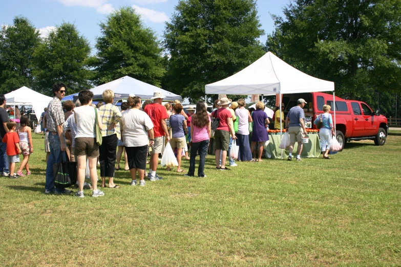 a large crowd stands by tents and listens to the speakers