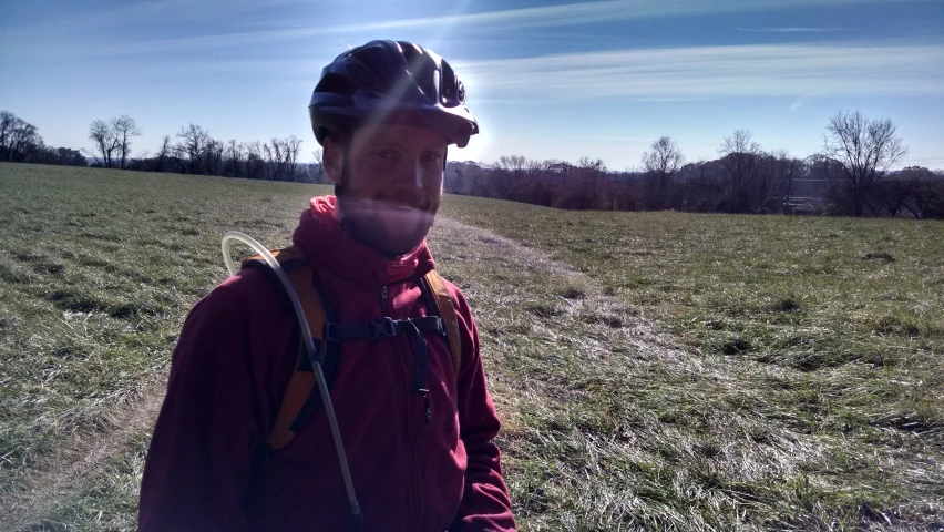 man with a hat standing on grass looking into camera