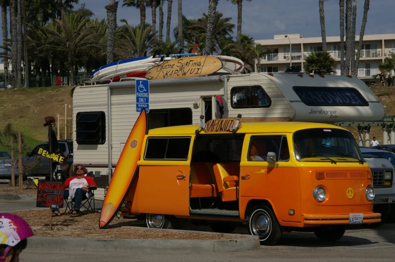 an old camper van parked in a parking lot with surfboard leaning against it