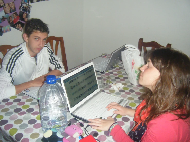 a man and woman sitting at a table using laptops