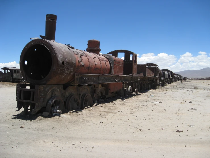 a rusted locomotive sitting on a dirt road