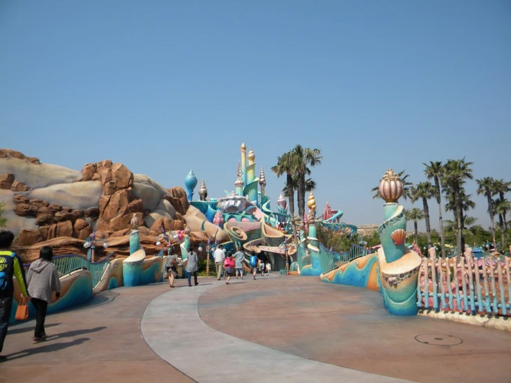 several people walk past brightly colored houses and palm trees