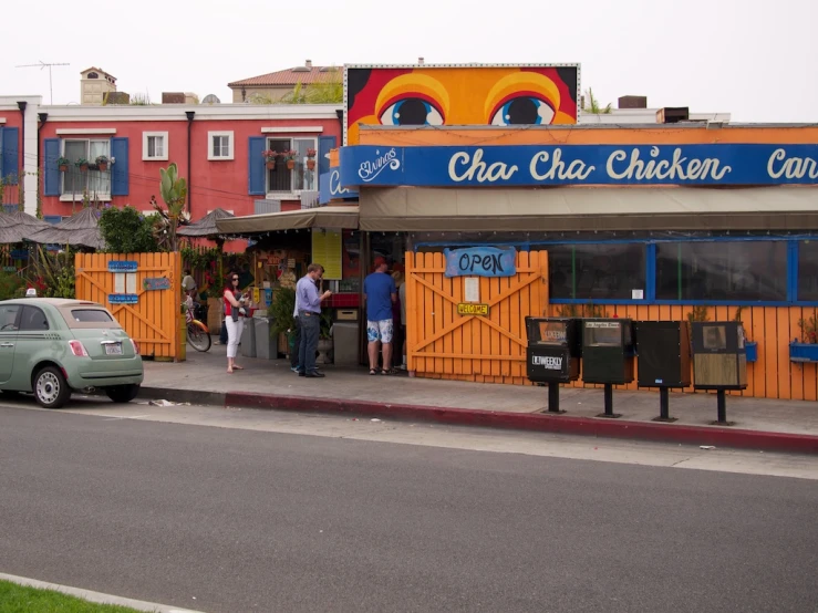 two people are standing in front of a chicken place